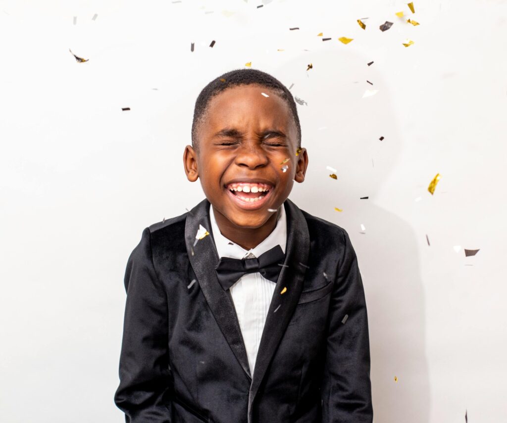 A young boy in a tuxedo laughing