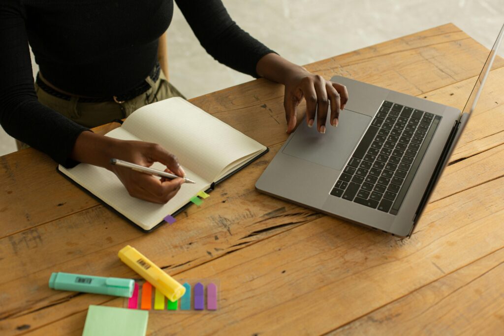 Tips for Overcoming Procrastination - crop-unrecognizable-black-woman-using-laptop-and-writing-notes